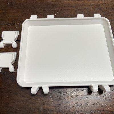 A plain white 3D-printed tray next to two small printed stands.