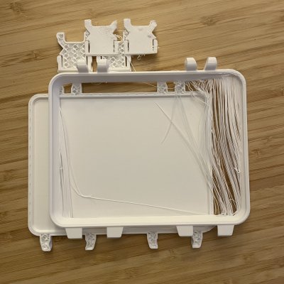 A failed print: the white tray covered in stringy strands of filament along one side.