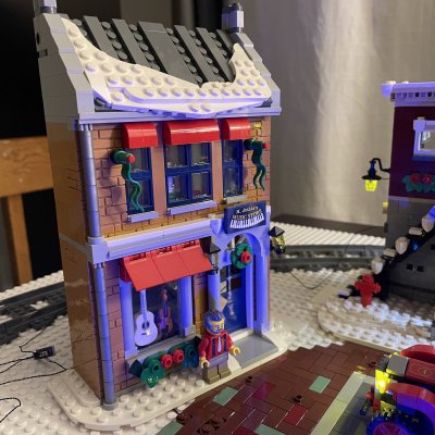 A LEGO music shop with purple trim, guitars in the window and a snowy roof at the edge of the village.