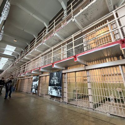 A long cellhouse corridor lined with two tiers of barred cells and a skylight running overhead.