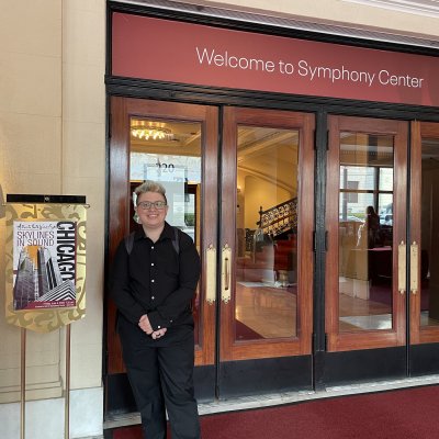 Andy in black concert clothes standing outside the Welcome to Symphony Center doors in Chicago.
