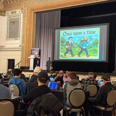 A full room watching a talk at WIRE LIVE, with a slide reading Once upon a time on the screen.