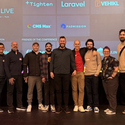 Speakers and organizers posing on the WIRE LIVE stage in front of the sponsor wall.